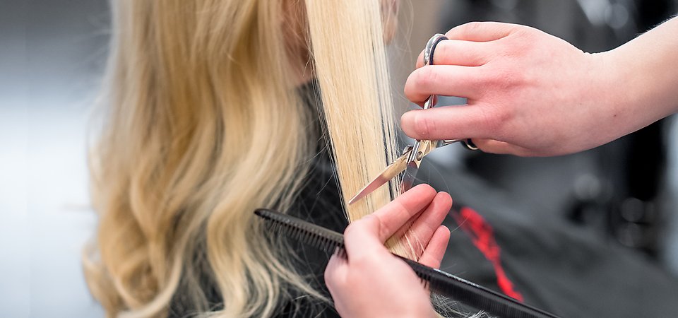 Elever sitter och pluggar i fåtöljer. En lärare samtalar med en elev.